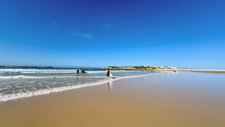 Weitläufiger Surfstrand in Baleal mit sanften Wellen und blauem Himmel.