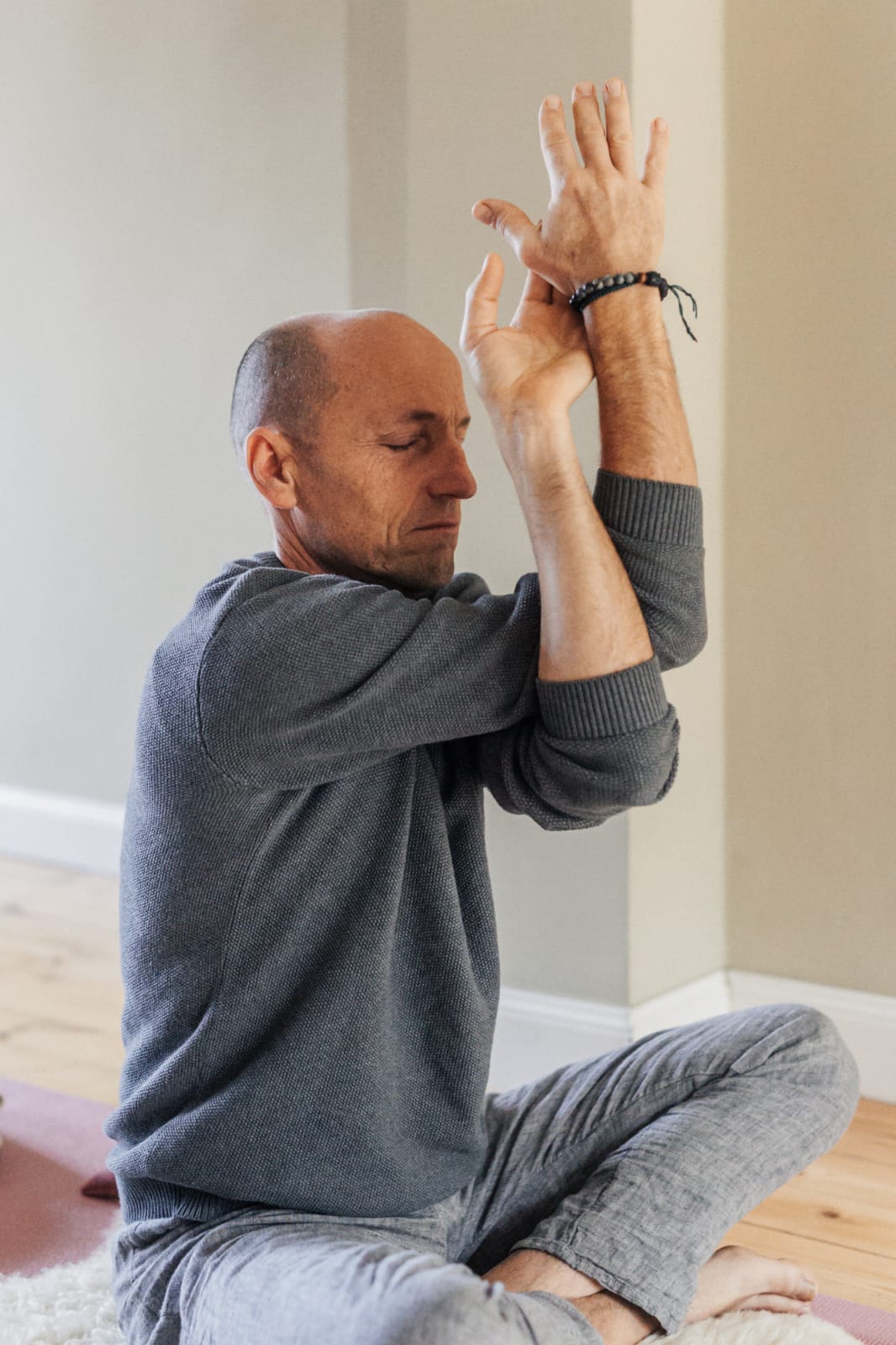 A man as a yoga teacher of the yoga retreat sits with crossed legs and makes a movement of yoga.