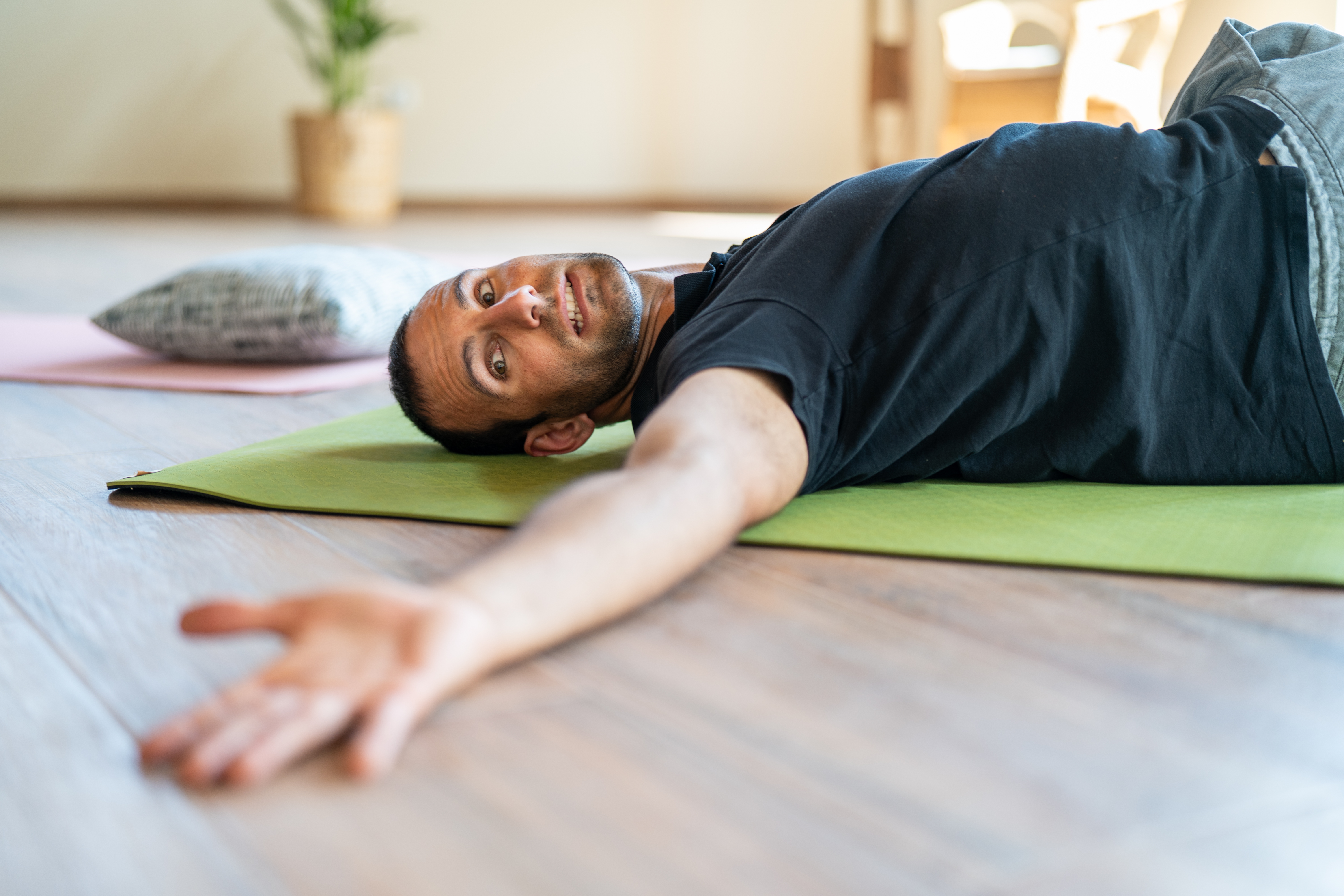 A man lies on the ground and is doing a movement of yoga at the yoga retreat in portugal.