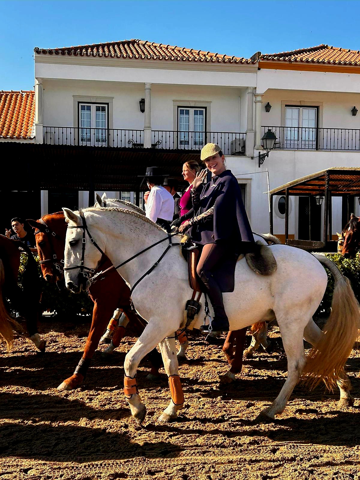 Frauen reiten auf Pferden im Sand beim Pferdefest Feira Nacional do Cavalo und winken in die Kamera.